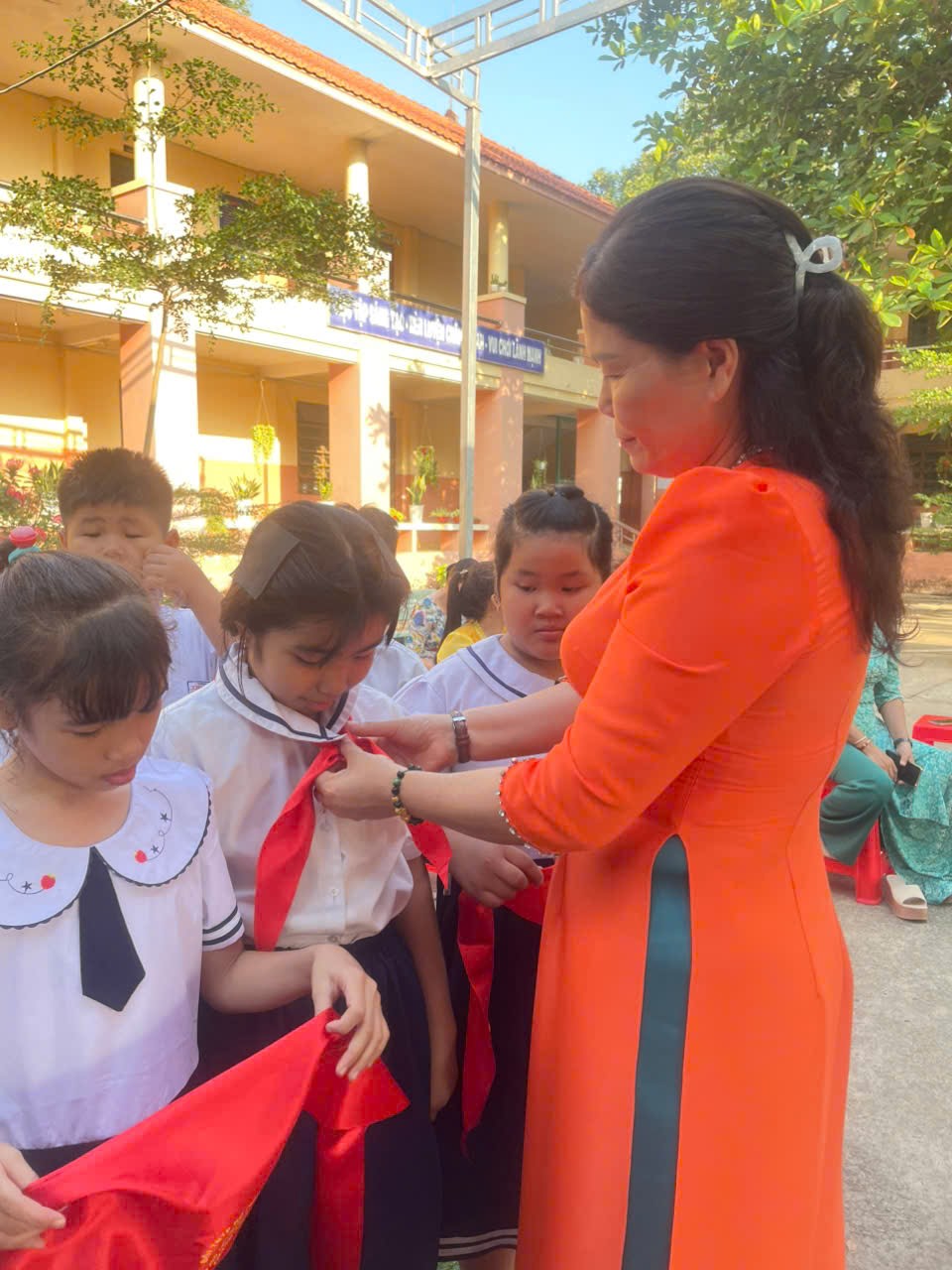 hình ảnh cô hiệu trưởng trao tặng khăn quàng cho học sinh kết nạp Đội